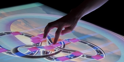 A person's hand touching a touch-table for a computer game at the Computer Science Games Day.