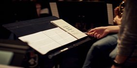 Conductor at a music stand leading musicians. 